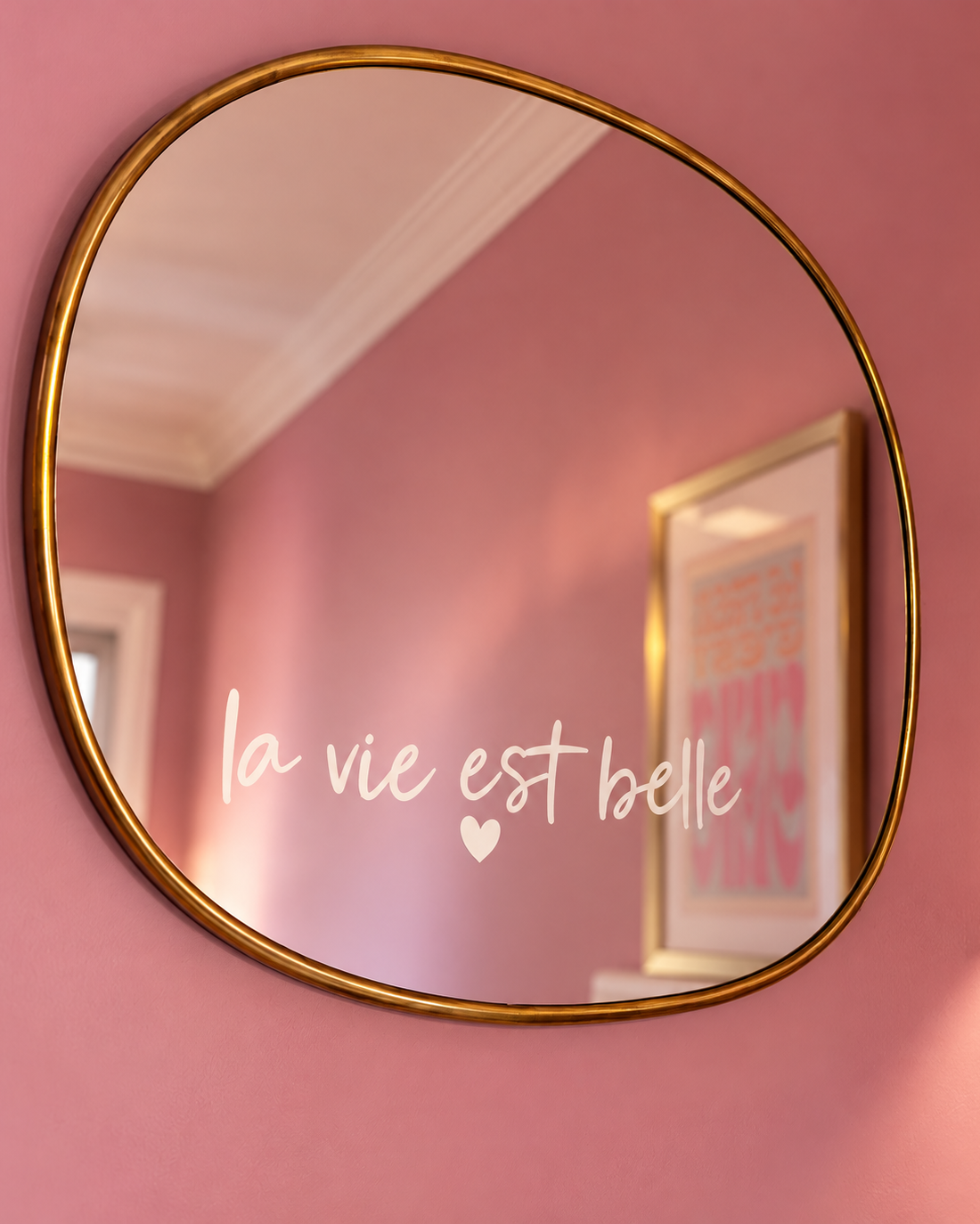 Miroir en laiton au mur avec le sticker « la vie est belle » posé sur le verre