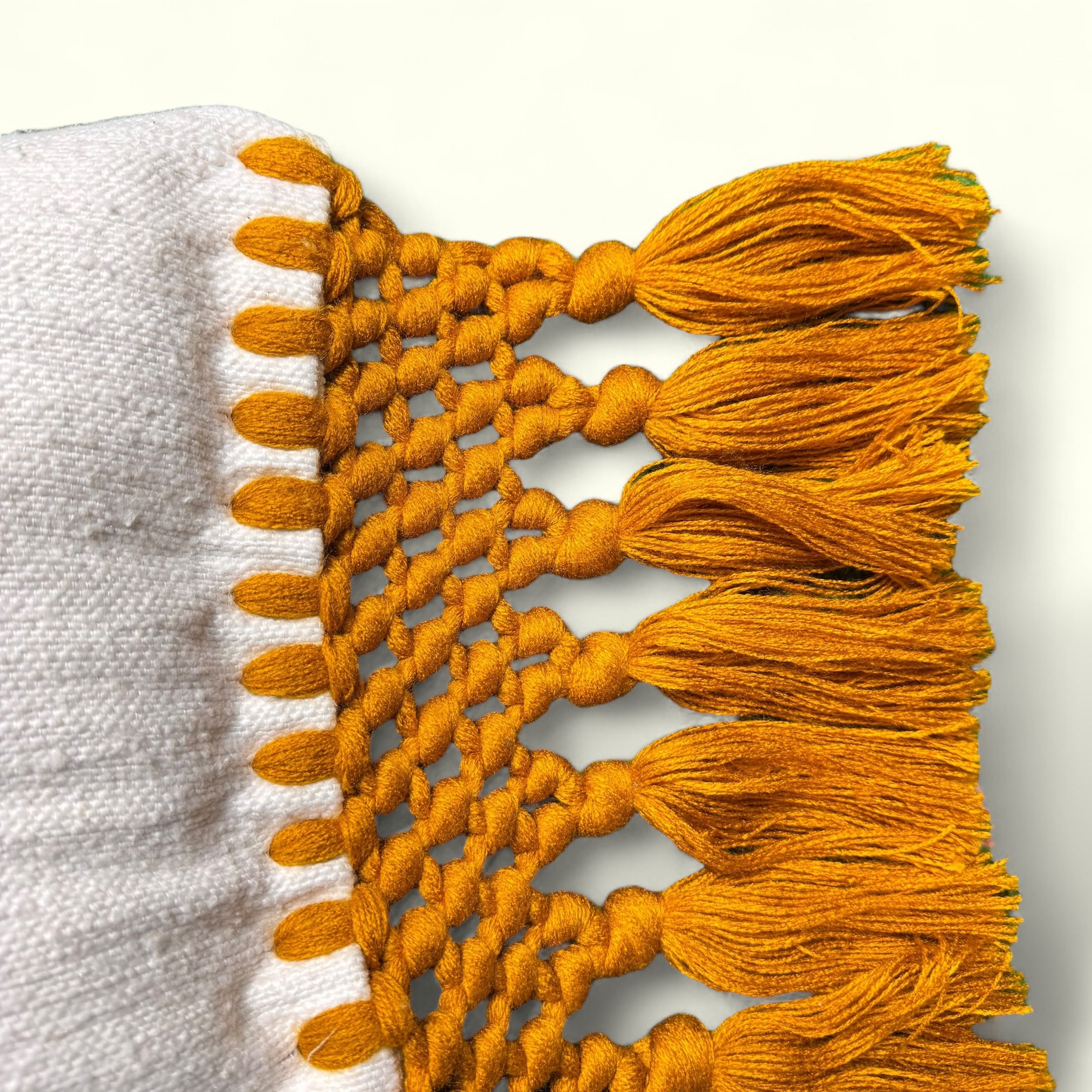 Franges et pompons orange d'une housse de coussin en macramé