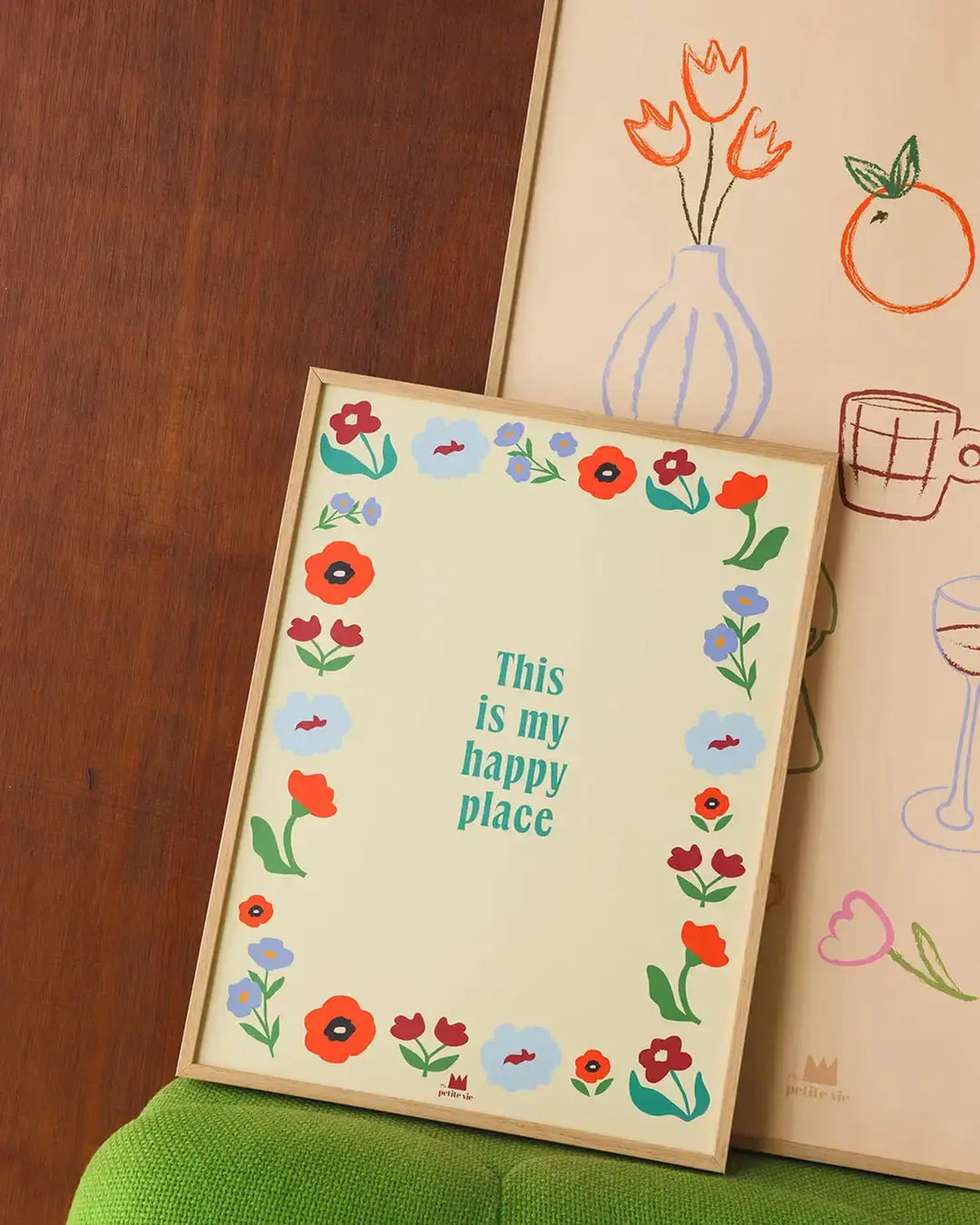 Affiche Happy place posée sur un fauteuil vert, dans un cadre bois (non inclus)