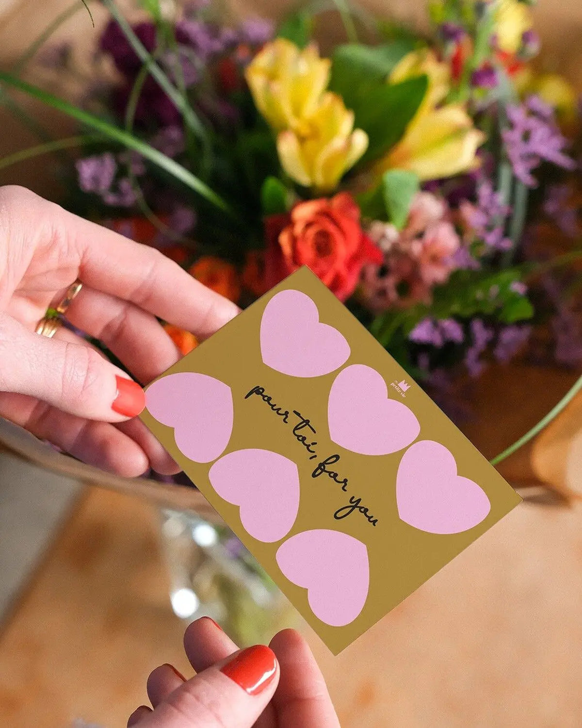 Mini carte Pour toi tenue en main devant un bouquet de fleurs