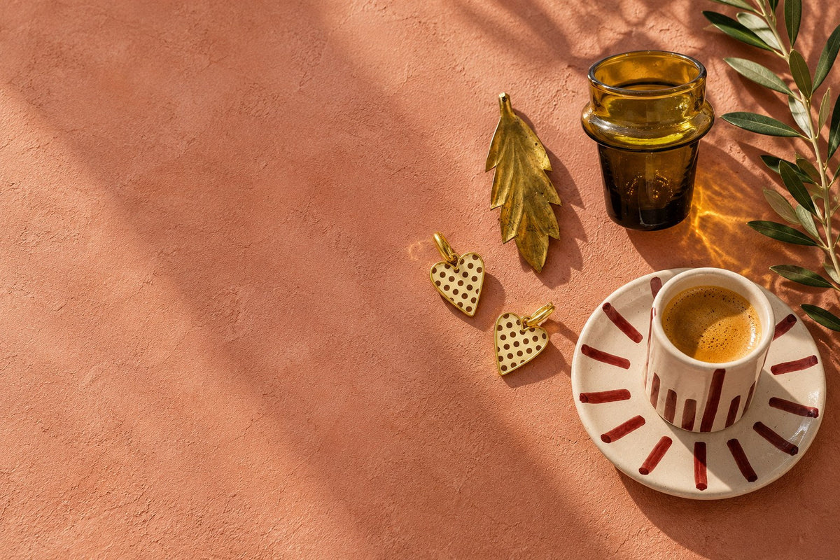 Nature morte au soleil : boucles d'oreilles cœur, feuille en laiton FULVIA, verre beldi et tasse MINA