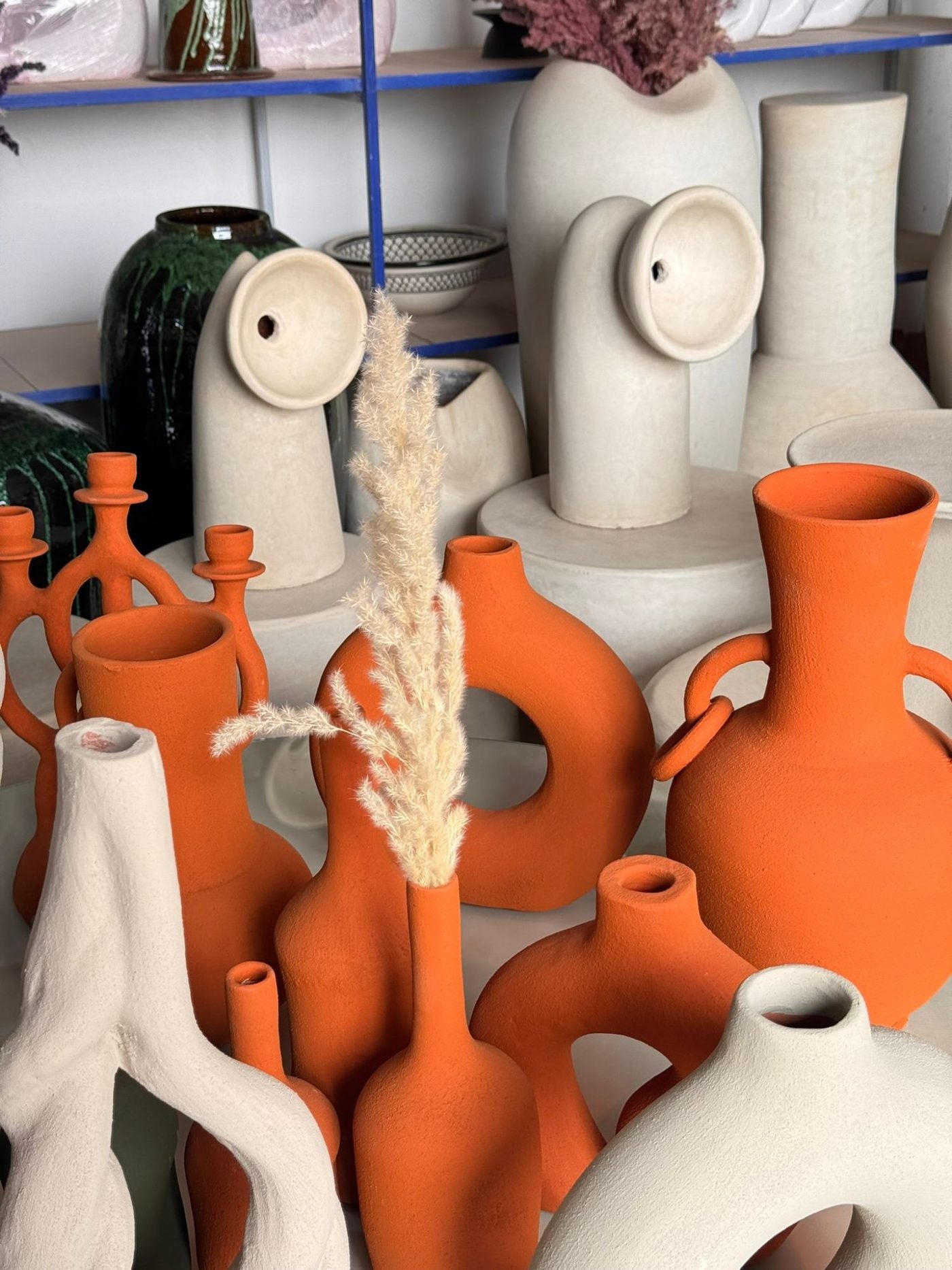 Vases et bougeoirs en terre orange et sable chez un artisan potier
